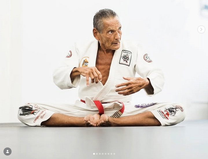 Grão-Mestre Relson Gracie sentado no tatame com kimono e faixa vermelha